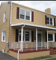 A yellow two-story house with a white front porch and red trim.