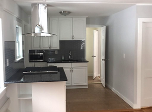 A clean, modern kitchen with white cabinets, black countertops, and stainless steel appliances.